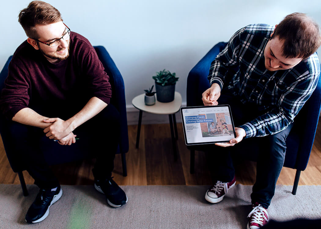 Sam holding an iPad with the St. Modwen website on whilst Mirek looks pleasely at it