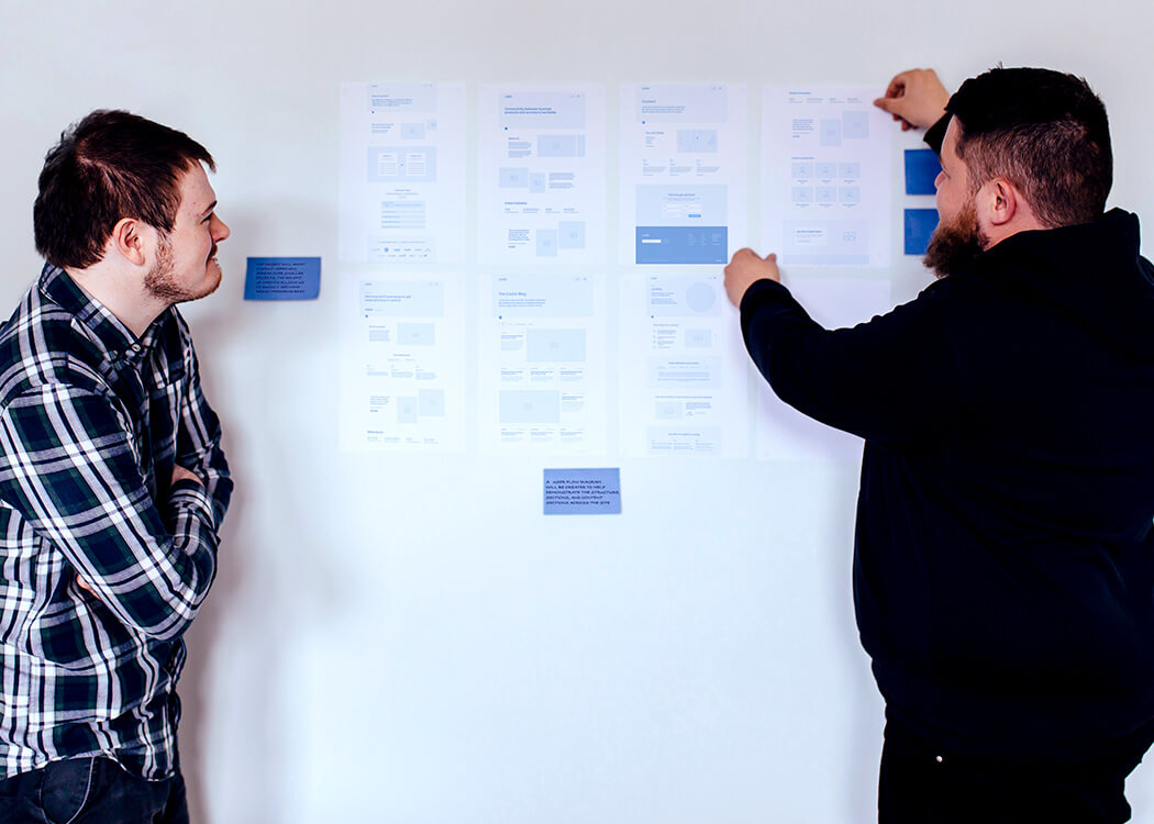 Liam and Sam smiling at some posters with indistinguishable blue pictures and text on it